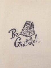 A "Be Grateful" Embroidered Flour Sack Towel with the word be grateful on it.
