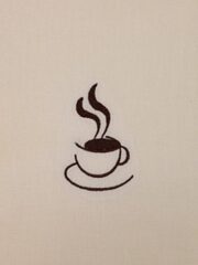 An image of a Coffee Embroidered Flour Sack Towel with a saucer on it.