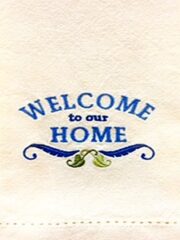 A "Welcome To Our Home" Cream Embroidered Hemstitched Hand Towel with the words welcome to our home on it.