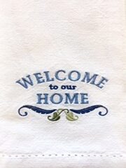 A "Welcome To Our Home" White Embroidered Hemstitched Hand Towel with the words welcome to our home.