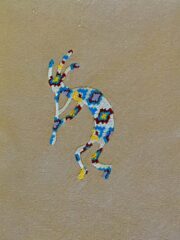 A beaded design of a Kokopelli (wheat) on a beige background.