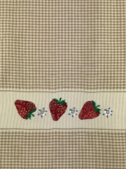 A kitchen towel with strawberries and flowers on it.
